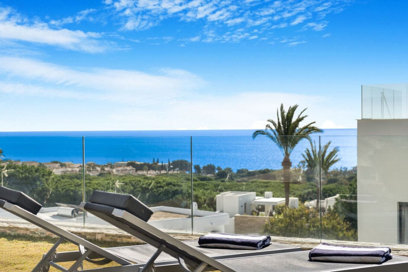 A balcony with sun loungers and a view of the sea.