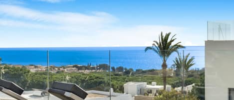 A balcony with sun loungers and a view of the sea.