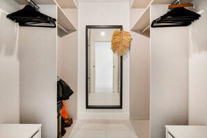 Un pasillo con un espejo, una puerta y un adorno colgante.