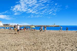 A beach with people, a pier, and a lighthouse. - Luxury Apartment with Ocean View (Marbella)