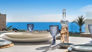 A table set with plates, glasses, and a bottle, overlooking a clear blue sky and sea. - Luxury Apartment with Ocean View (Marbella)