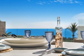 A table set with plates, glasses, and a bottle, overlooking a clear blue sky and sea. - Luxury Apartment with Ocean View (Marbella)