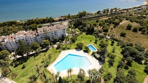 Ett hotell med pool, omgivet av grönska och med utsikt över havet.