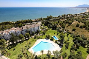A hotel with a pool, surrounded by greenery and a view of the sea. - Marbella La Ola: 9th floor (Marbella)