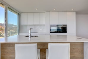 A modern kitchen with a large island, white cabinetry, and a view of the landscape. - Marbella La Ola: 9th floor (Marbella)