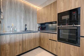 A modern kitchen with wooden cabinets, a double oven, and a stainless steel countertop. - Portside Suite, Puerto Banús (Marbella)
