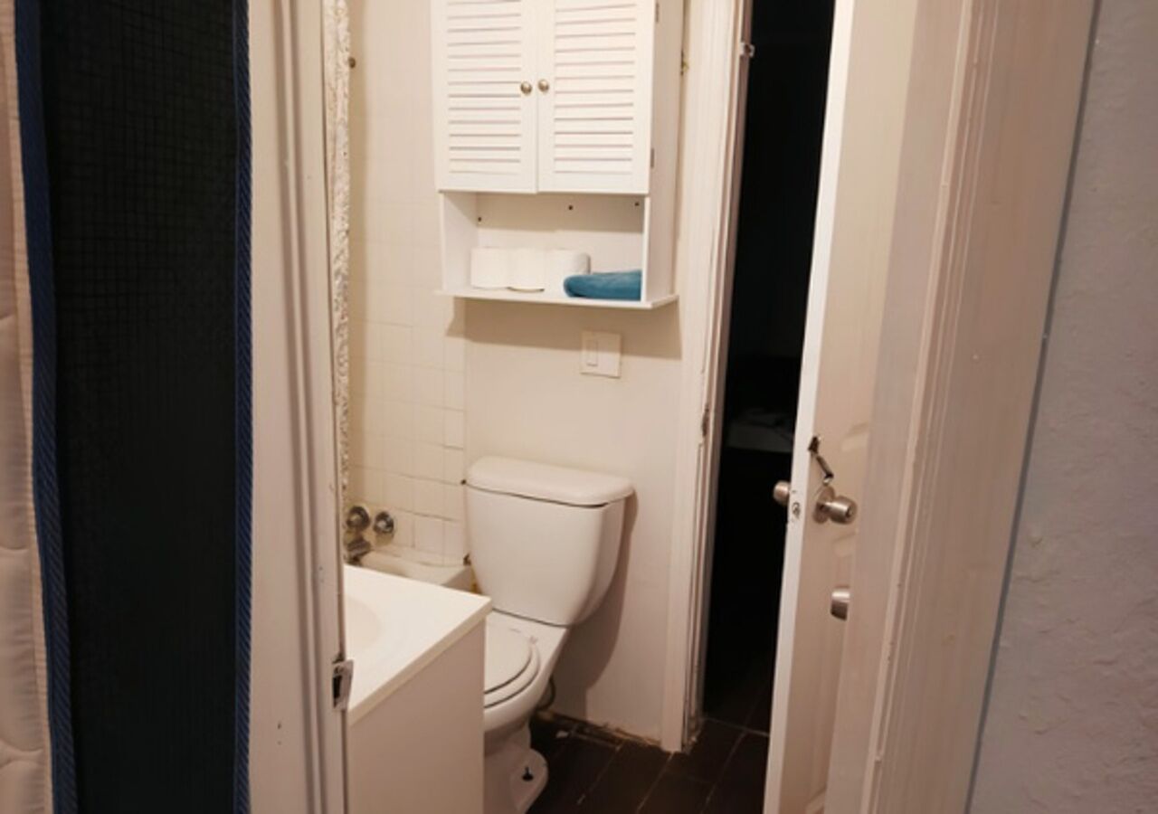 Une petite salle de bain comprenant des toilettes, un lavabo et un meuble de rangement au-dessus des toilettes.