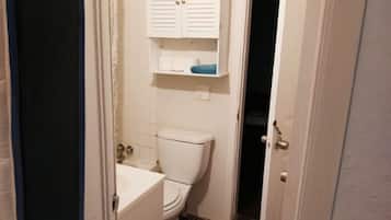 Une petite salle de bain comprenant des toilettes, un lavabo et un meuble de rangement au-dessus des toilettes.