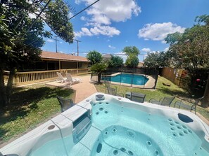 A backyard with a hot tub, a swimming pool, and a covered patio area. - Backyard Paradise by Lackland Pool+Hot tub+King Beds+Games (San Antonio)