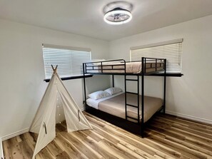Ein Zimmer mit Etagenbetten, einem Zelt und einem Deckenventilator.