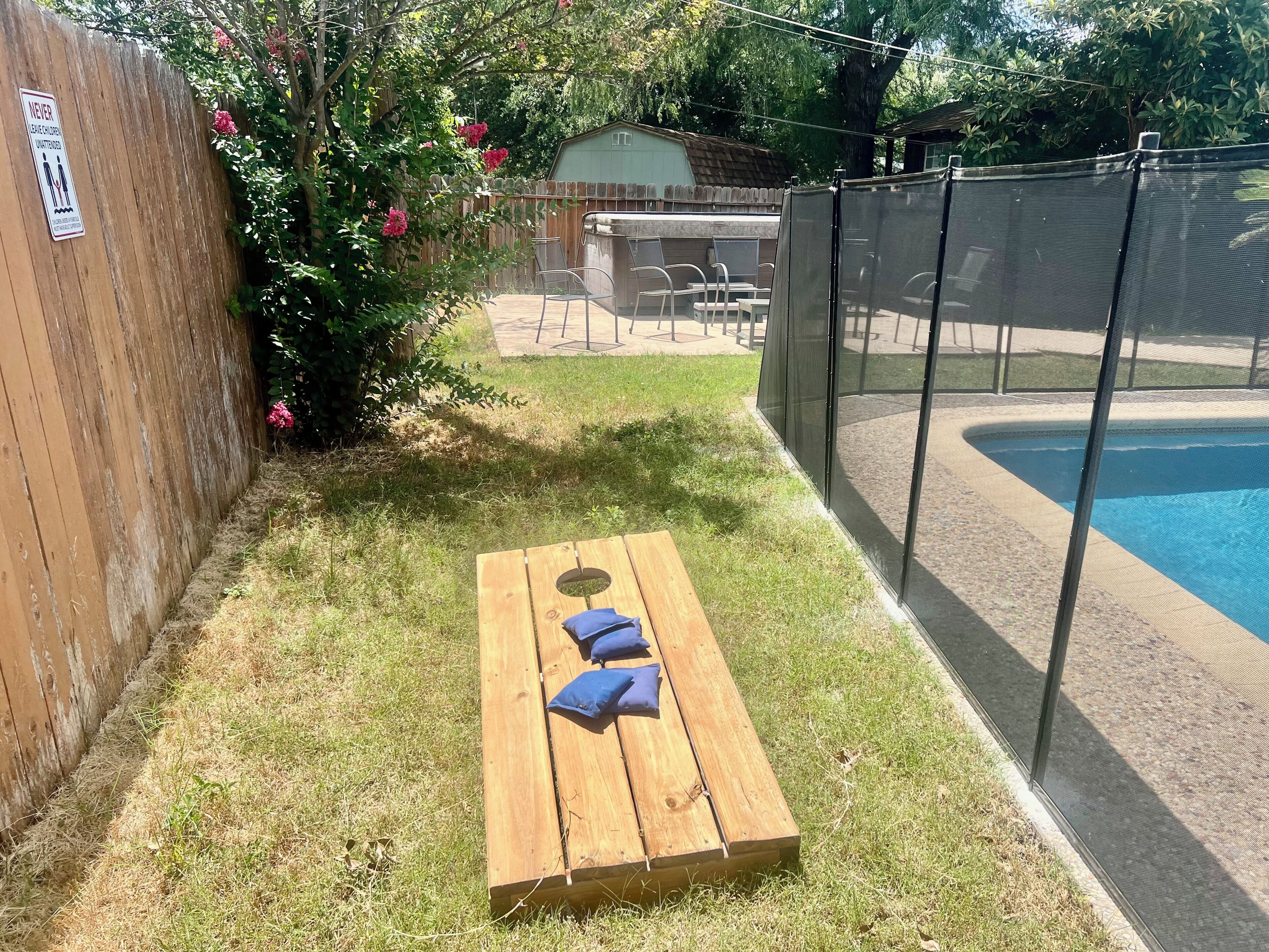 Eine Holzterrasse mit Schwimmbecken, einem eingezäunten Bereich und einem Schild am Zaun.