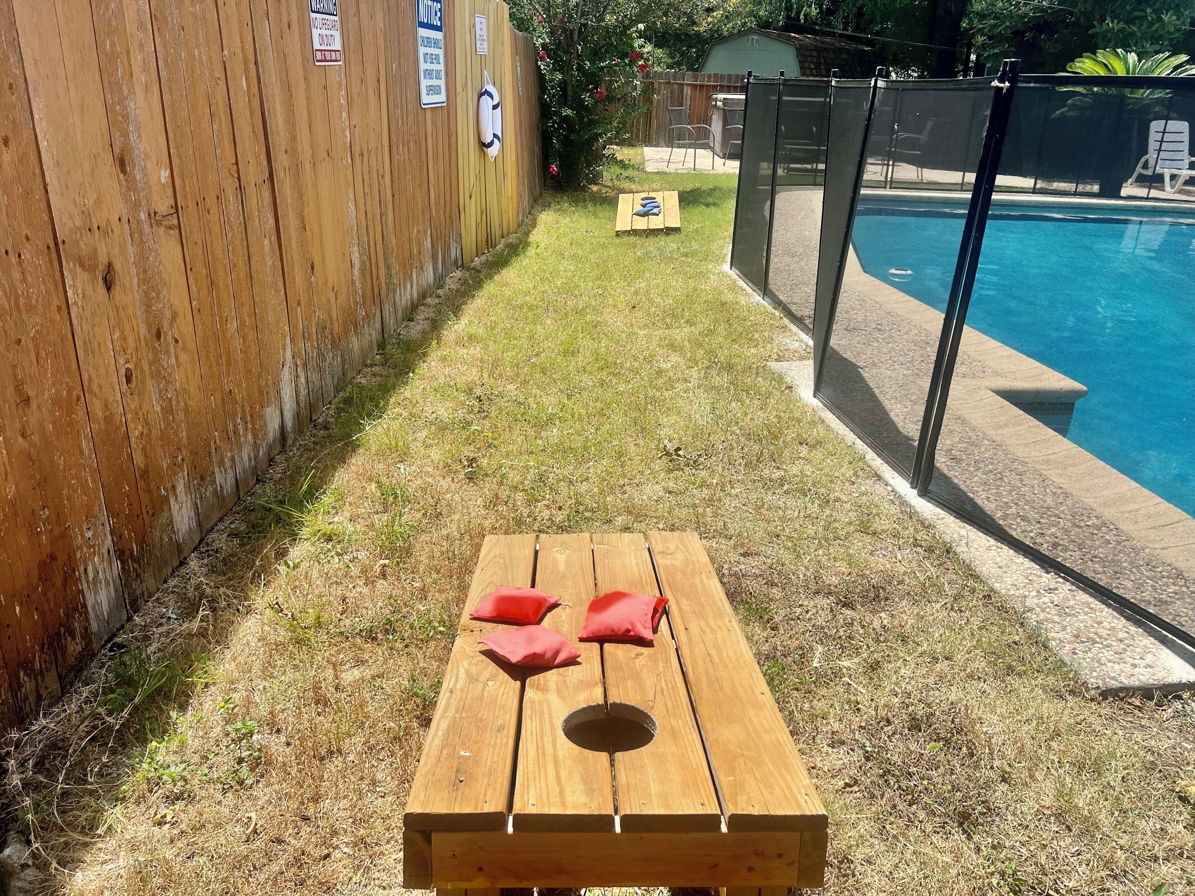 Une terrasse en bois avec une table de pique-nique, une piscine et une clôture en bois agrémentée de panneaux d’avertissement.