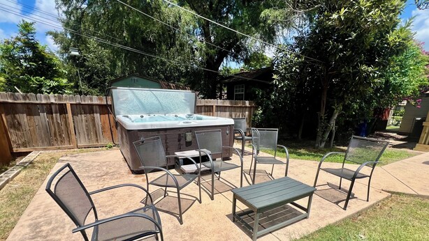 An outdoor patio with a hot tub, metal chairs, and a table. - Backyard Paradise by Lackland Pool+Hot tub+King Beds+Games (San Antonio)
