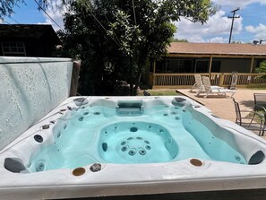 Ein Whirlpool mit zahlreichen Düsen, umgeben von einer Holzterrasse und Gartenmöbeln.