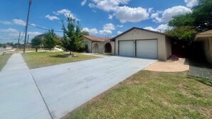 A residential property with a garage, a sidewalk, and a clear sky. - Backyard Paradise by Lackland Pool+Hot tub+King Beds+Games (San Antonio)