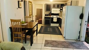 A compact kitchen with a dining table and chairs, a refrigerator, and a microwave.