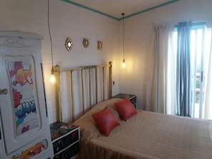 A bedroom with a bed, a dresser, a nightstand, and a window with curtains.