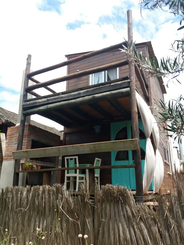 A two-story wooden building with a balcony, a staircase, and a window.