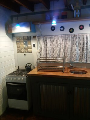 A kitchen with a gas stove, oven, and a wooden countertop with a sink.