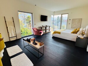 A modern living room with a sofa, a coffee table, and a TV mounted on the wall. - VILLA AQUA LUXURY DESIGN - LAKE COMO VIEW - TREMEZZINA-100 METERS FROM THE SHORE (Tremezzina)
