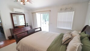 Un dormitorio con cama, cómoda, espejo y ventanas.