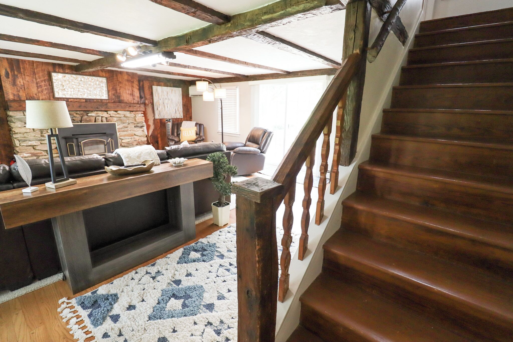 A cozy living area with a fireplace, a sofa, a coffee table, and a staircase.