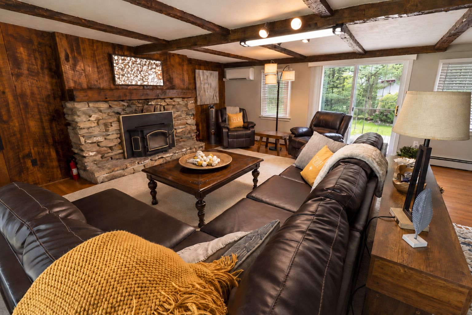A cozy living room with a stone fireplace, leather sofas, and a coffee table.