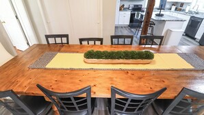 Una mesa de comedor de madera con una planta decorativa en el centro, rodeada de sillas.