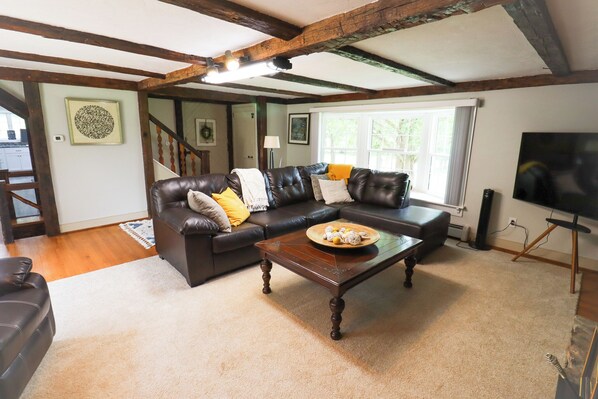 A living room with a dark brown leather sofa, a wooden coffee table, and a television on a stand.