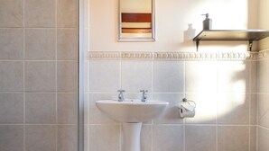 Een badkamer met een wastafel op voetstuk, een toilet en een handdoekhouder.