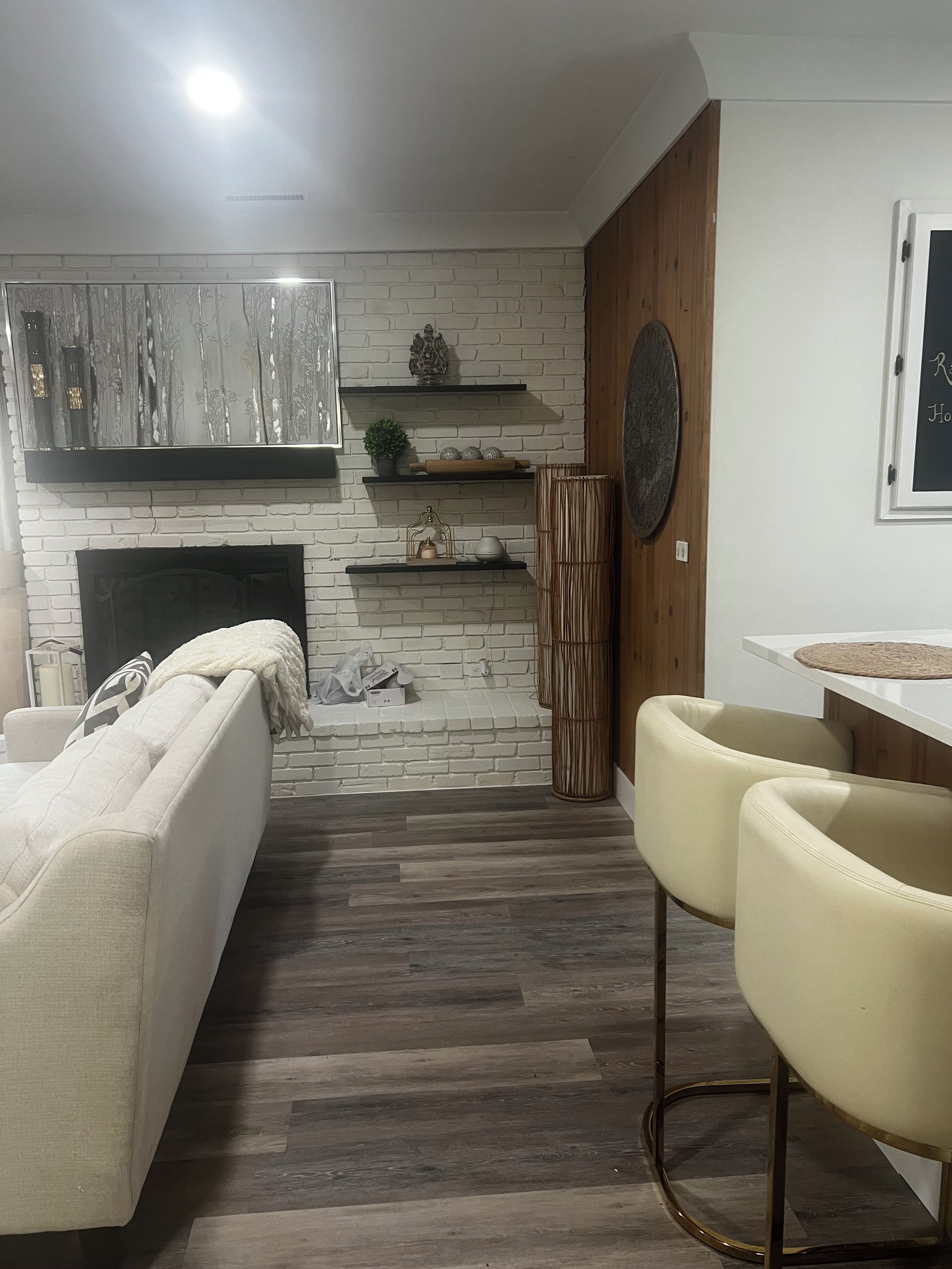 A modern living room with a fireplace, white brick wall, and wooden flooring.