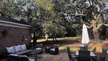 An outdoor patio with a brick wall, a sofa, a dining table, and chairs.