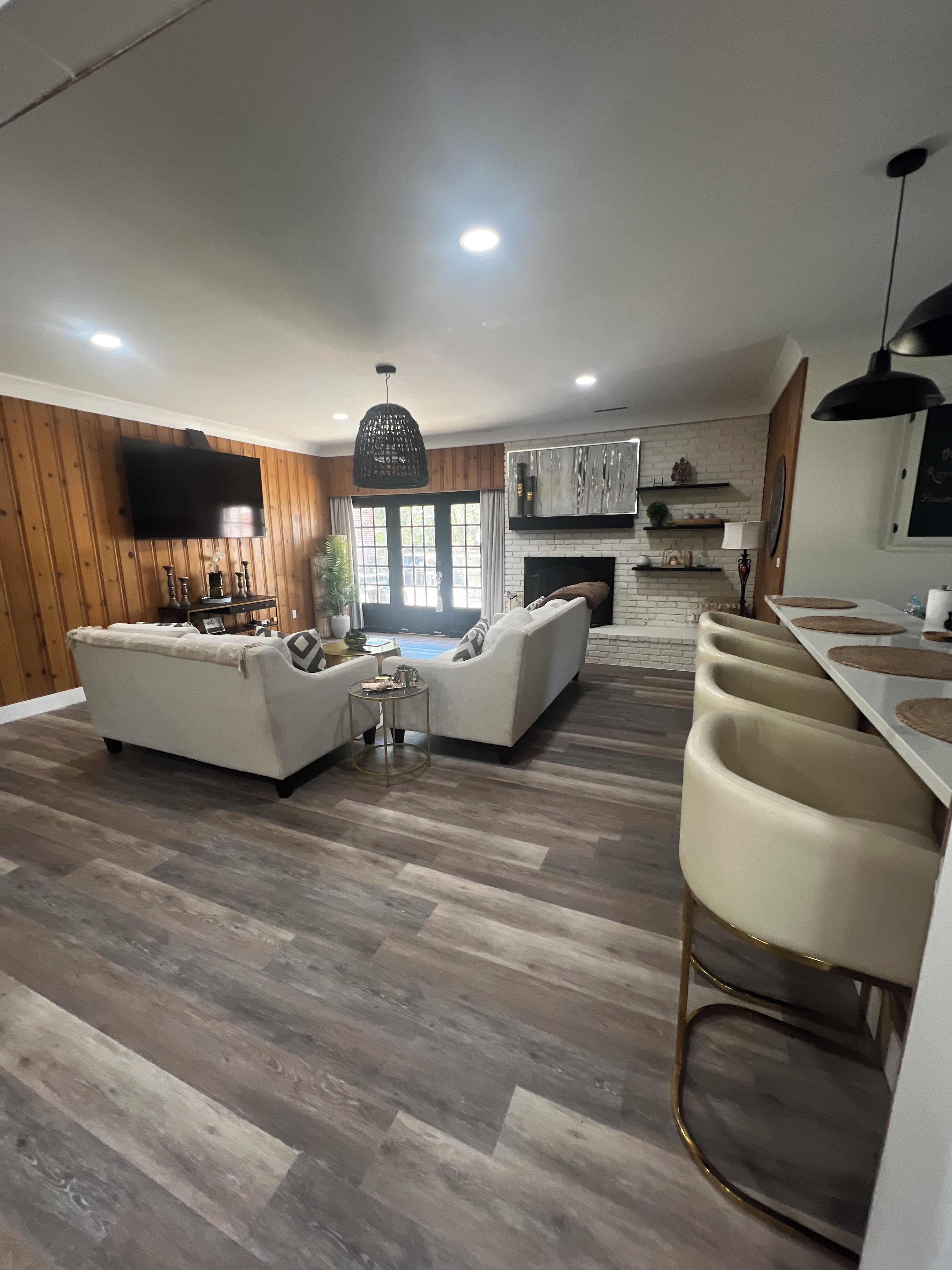 A spacious living area with a fireplace, a television mounted on the wall, and a dining area with bar stools.