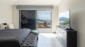 Une chambre moderne avec un lit, une télévision et un balcon offrant une vue sur la mer.
