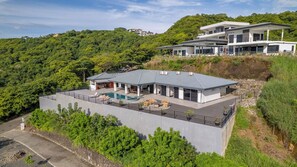 A modern two-story house with a swimming pool, surrounded by lush greenery and hills. - New Listing • Casa Hermosa Vista • 5BR Private Villa • Ocean View (Playas del Coco)