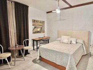 A bedroom with a bed, a desk, a chair, and a ceiling fan.
