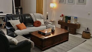 Ett vardagsrum med en soffa i läder, ett soffbord i trä och en bokhylla.