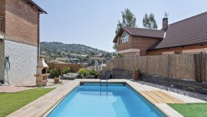 A rectangular swimming pool with a wooden deck and a ladder, surrounded by a wooden fence and a grassy lawn.