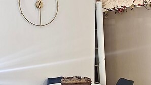 A round table with four chairs, a decorative item on the table, and a wall clock.