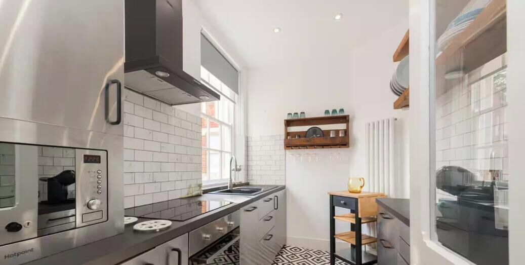 Cocina moderna con horno integrado, campana extractora de acero inoxidable y encimera negra.