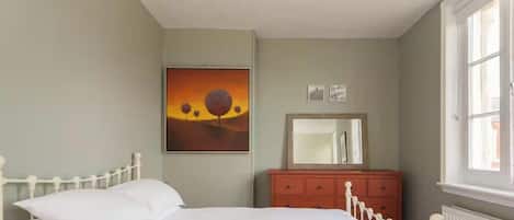 Un dormitorio con cama, cómoda, espejo y un cuadro en la pared.