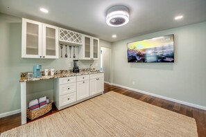 A modern kitchen with white cabinetry, a granite countertop, and a large wall-mounted TV displaying a sunset scene. - Villa Fun In The Sun, Lakefront Oasis with Heated Pool & Private Dock........ (Cape Coral)