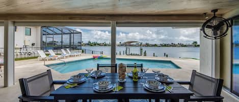 A dining area with a view of a pool and waterfront.