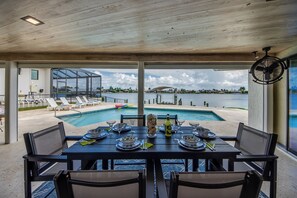 A dining area with a view of a pool and waterfront. - Villa Fun In The Sun, Lakefront Oasis with Heated Pool & Private Dock........ (Cape Coral)
