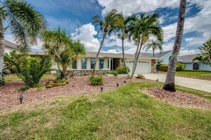 A residential property with a stone facade, a covered porch, and a well-maintained lawn with palm trees. - Villa Fun In The Sun, Lakefront Oasis with Heated Pool & Private Dock........ (Cape Coral)