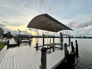 A wooden dock extending into calm water with a covered seating area and a clear sky. - Villa Fun In The Sun, Lakefront Oasis with Heated Pool & Private Dock........ (Cape Coral)