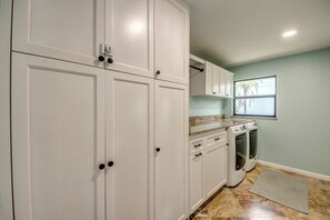 A kitchen with white cabinets, a countertop, a stove, and a window with a view of palm trees. - Villa Fun In The Sun, Lakefront Oasis with Heated Pool & Private Dock........ (Cape Coral)