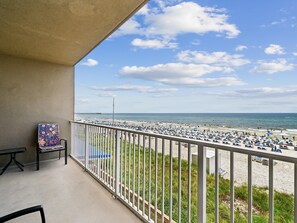 Ein Balkon mit Blick auf einen Strand, ein Tisch und ein Stuhl.