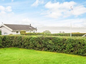 A residential property with a house, a lawn, and a body of water in the background. - 4 Star Holiday Home in Hejls (Hejls)