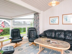 Un salon avec un canapé en cuir noir, deux fauteuils en cuir, une petite table ronde et une table basse.
